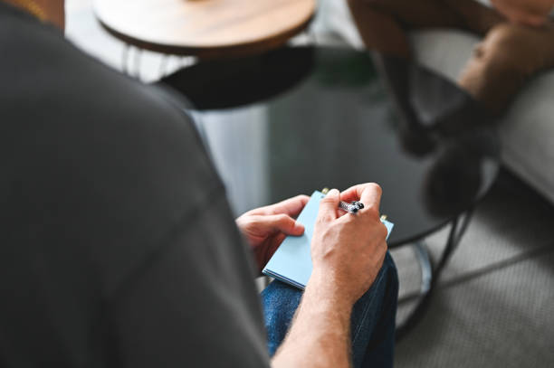 close up young mental health professional takes notes during session